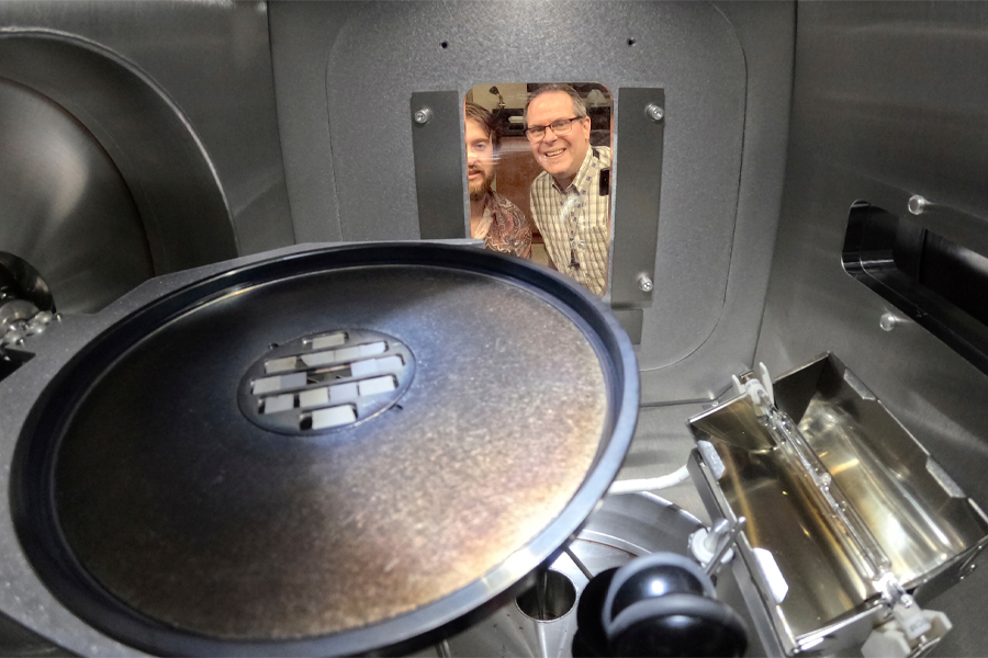 Andre Juliao, left, a doctoral student, and Lance Cooley, a professor of Mechanical Engineering and director of the Applied Superconductivity Center, observing a thin-film deposition of niobium for high-field cavities for axion dark matter detection. (Mark Wallheisier/FAMU-FSU College of Engineering)