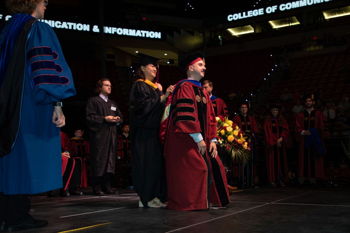 A Florida State University faculty hoods a doctoral graduate the summer doctoral hooding ceremony Friday, Aug. 4, 2023, at the Donald L. Tucker Civic Center. (FSU Photography)