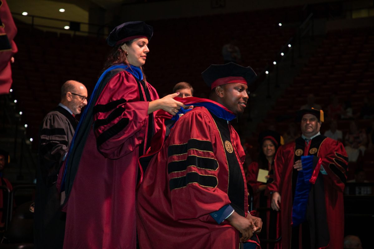 A Florida State University faculty hoods a doctoral graduate the summer doctoral hooding ceremony Friday, Aug. 4, 2023, at the Donald L. Tucker Civic Center. (FSU Photography)