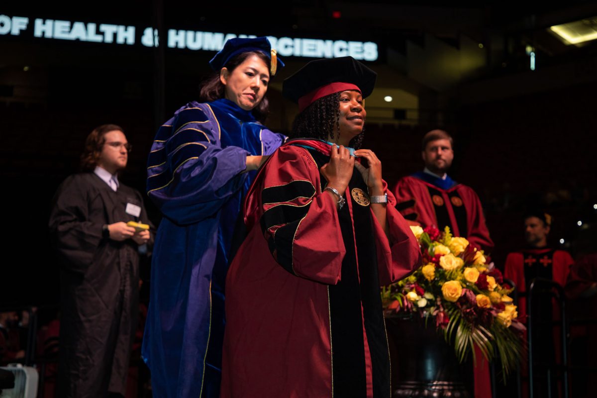 A Florida State University faculty hoods a doctoral graduate the summer doctoral hooding ceremony Friday, Aug. 4, 2023, at the Donald L. Tucker Civic Center. (FSU Photography)