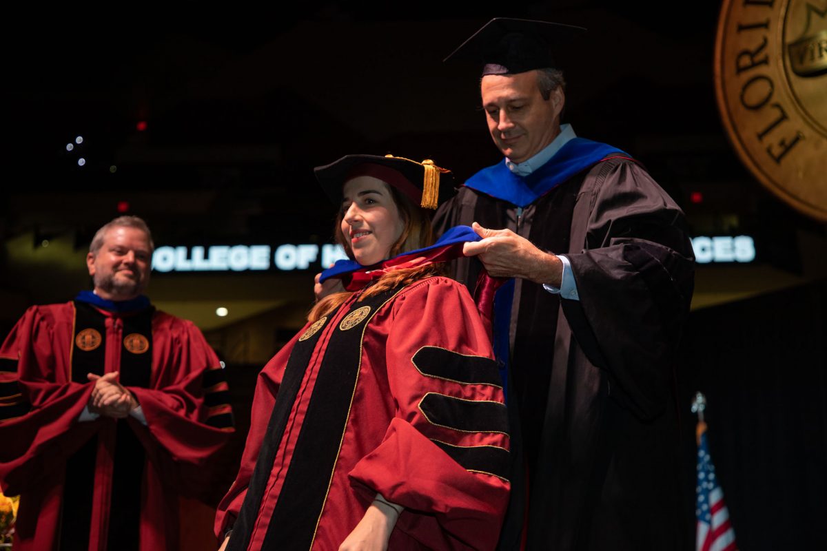 A Florida State University faculty hoods a doctoral graduate the summer doctoral hooding ceremony Friday, Aug. 4, 2023, at the Donald L. Tucker Civic Center. (FSU Photography)