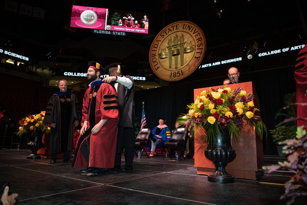 A Florida State University faculty hoods a doctoral graduate the summer doctoral hooding ceremony Friday, Aug. 4, 2023, at the Donald L. Tucker Civic Center. (FSU Photography)