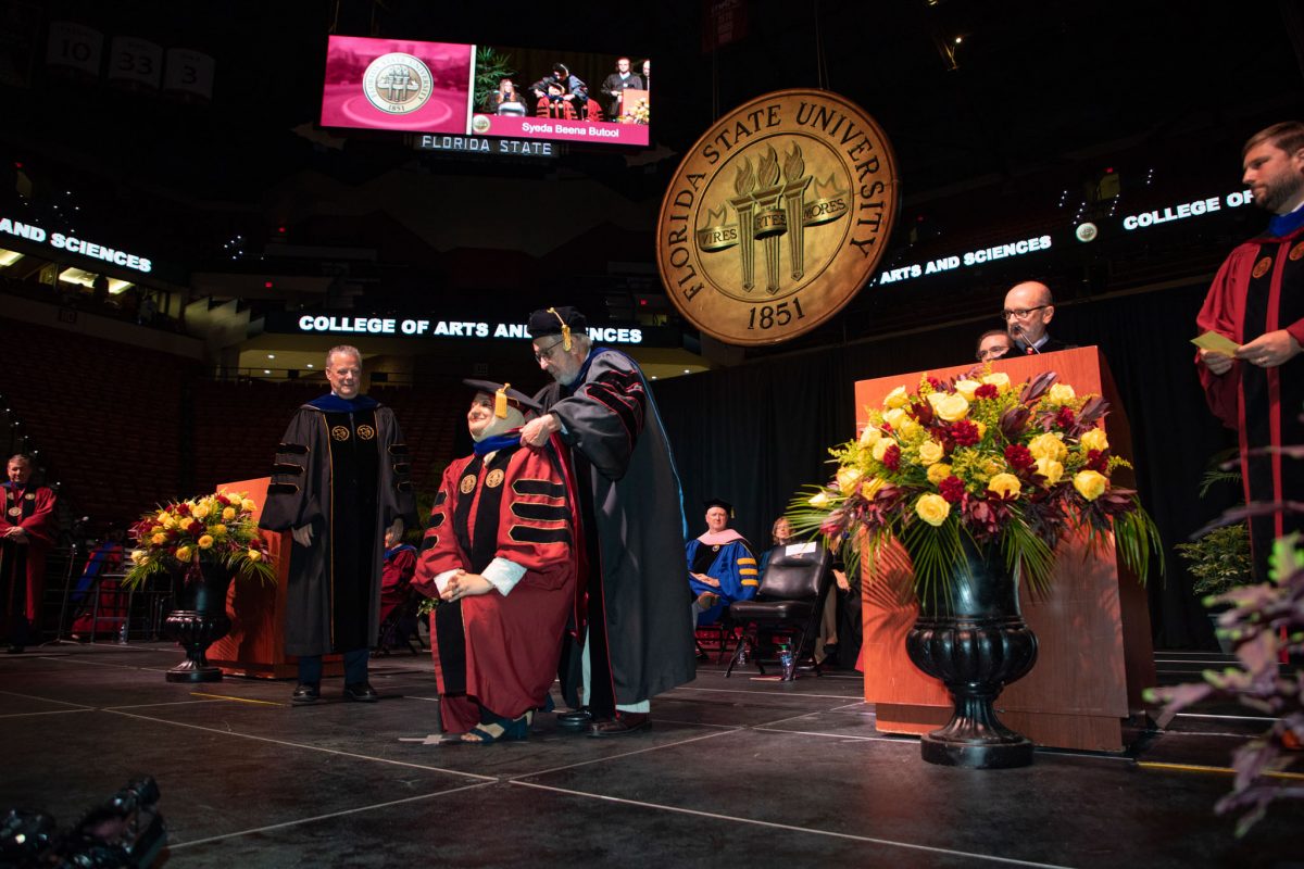 A Florida State University faculty hoods a doctoral graduate the summer doctoral hooding ceremony Friday, Aug. 4, 2023, at the Donald L. Tucker Civic Center. (FSU Photography)