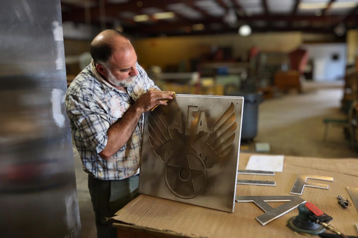 Master Craftsman Mark Dickson sanding the chamfer, a transitional rounded edge between the faces of the AFA emblem piece. (Photo: FSU Facilities)