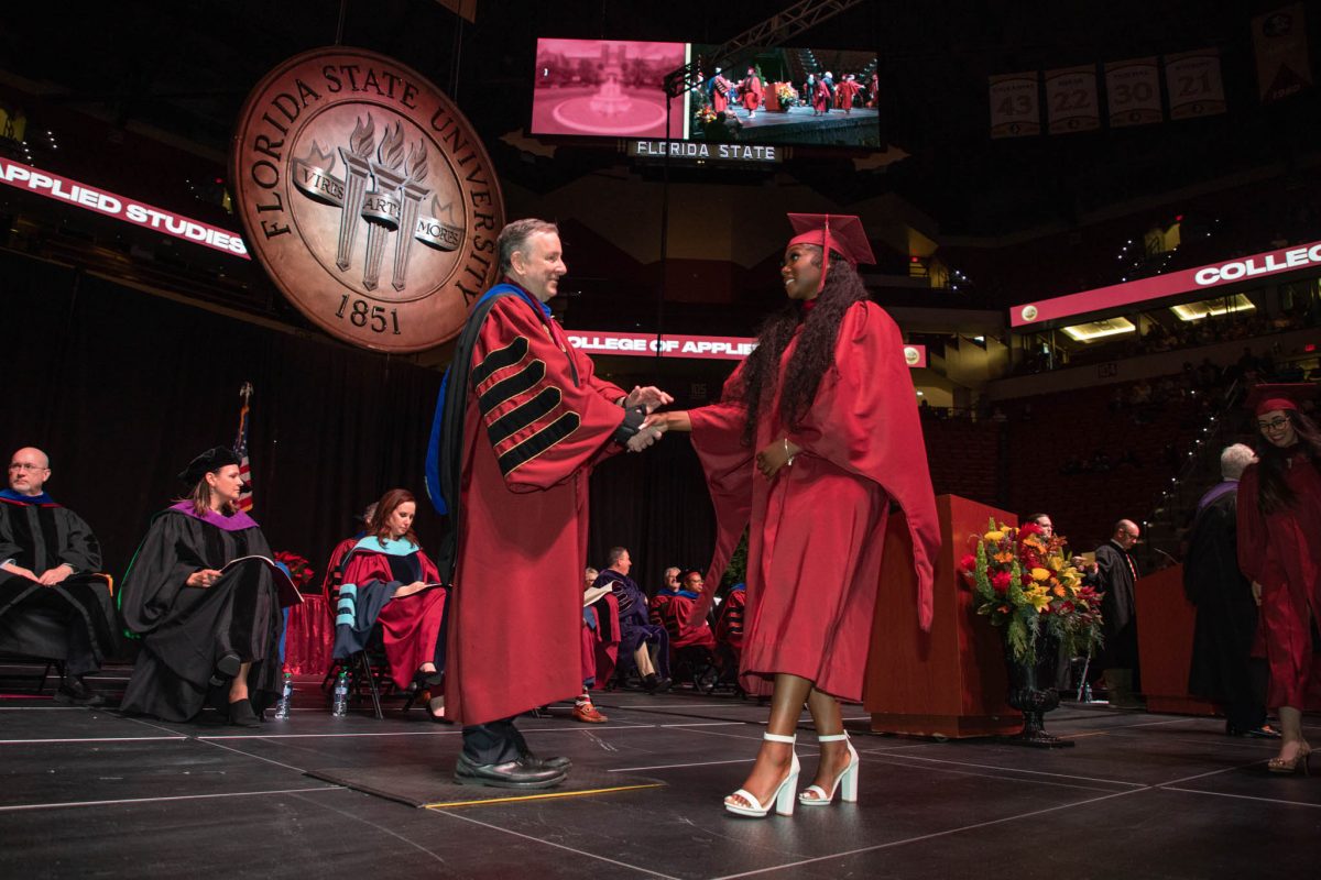 President Richard McCullough congratulates a graduate during commencement Friday, Dec. 15, 2023, at the Donald L. Tucker Civic Center. (FSU Photography Services)