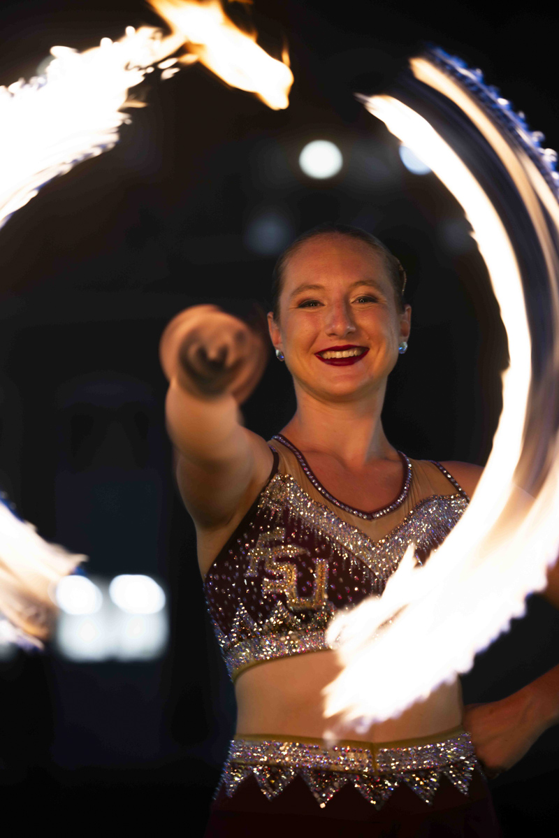 Mikayla Schuller, FSU Marching Chiefs Feature Twirler, twirls a fire baton in front of Doak Campbell Stadium. (Matthew McConnell/Florida State University)