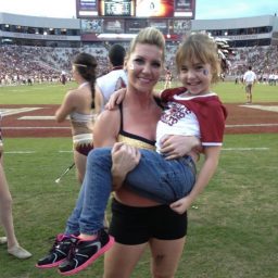 Kylee Saltsman as a child with her coach at an FSU football game.