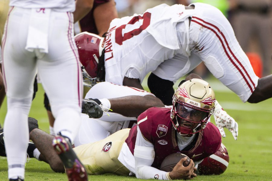 Football players, one on the ground holding a football