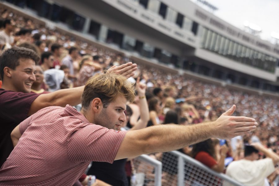 Two men in football stands hold our their hands
