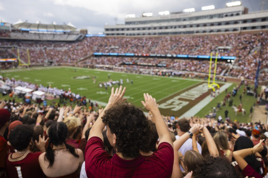 Someone in the stands of a football game holds their hands out