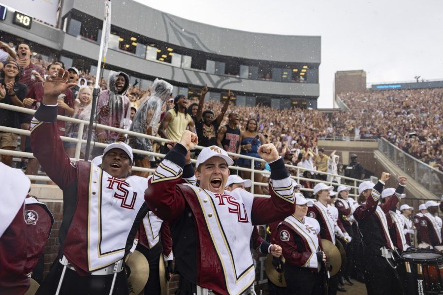 Members of FSU's Marching Chiefs celebrate with their hands up at a football game