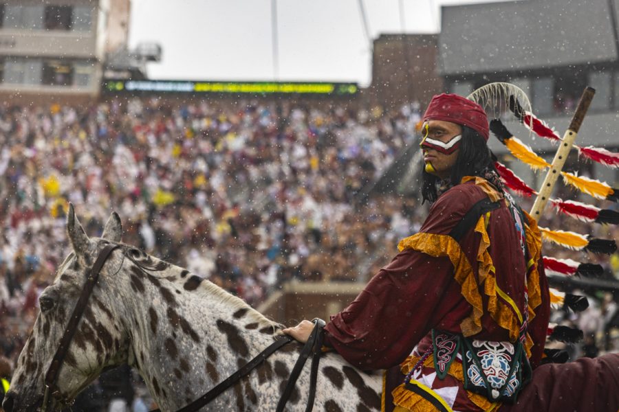 A man on a horse, at a football game, looks off in the distance