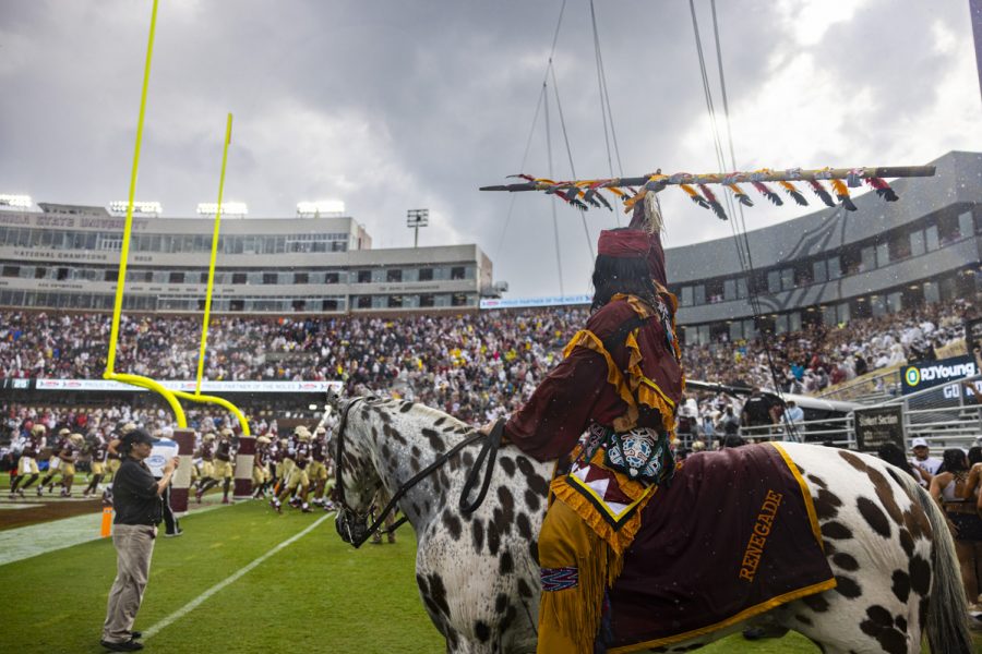 A man on a horse holds up a spear at a football game