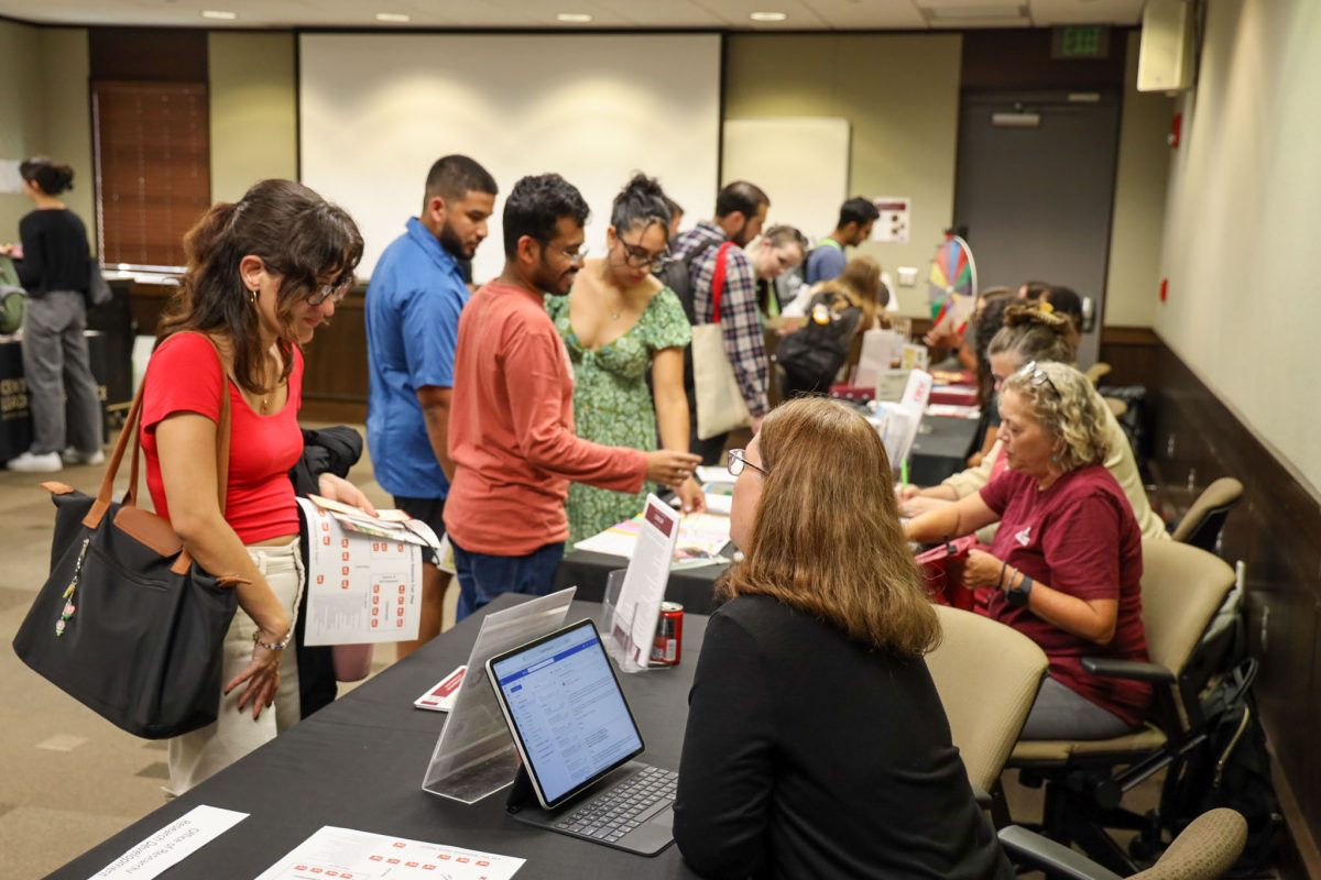 People sitting at tables talk to students