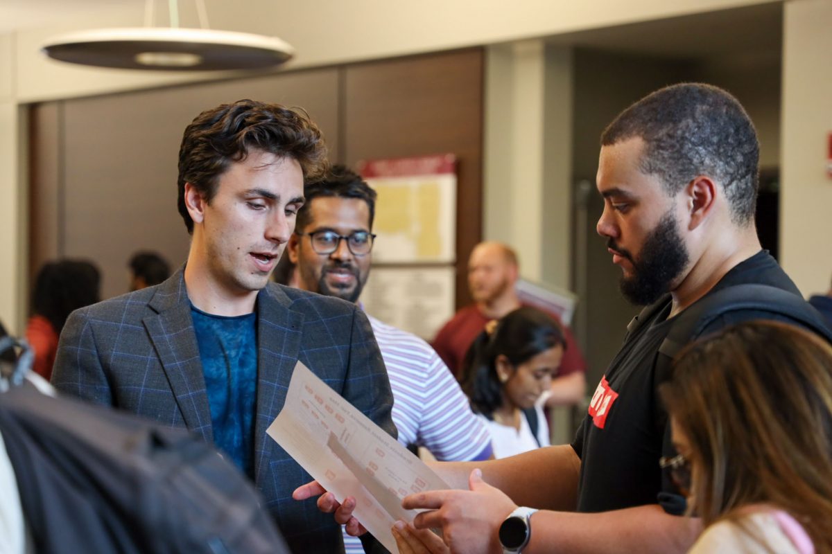 Two men speak, looking at a piece of paper