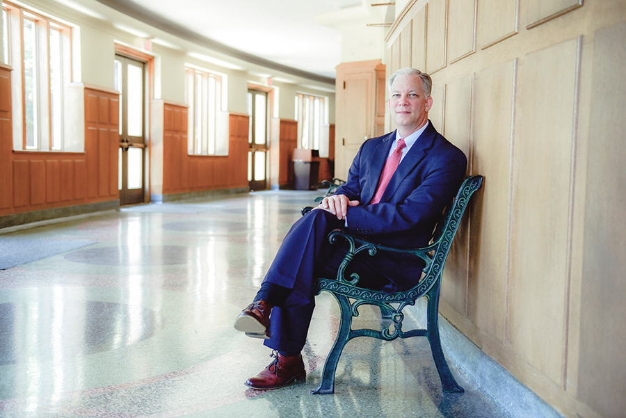 A man sits on a bench in a building turning to the camera