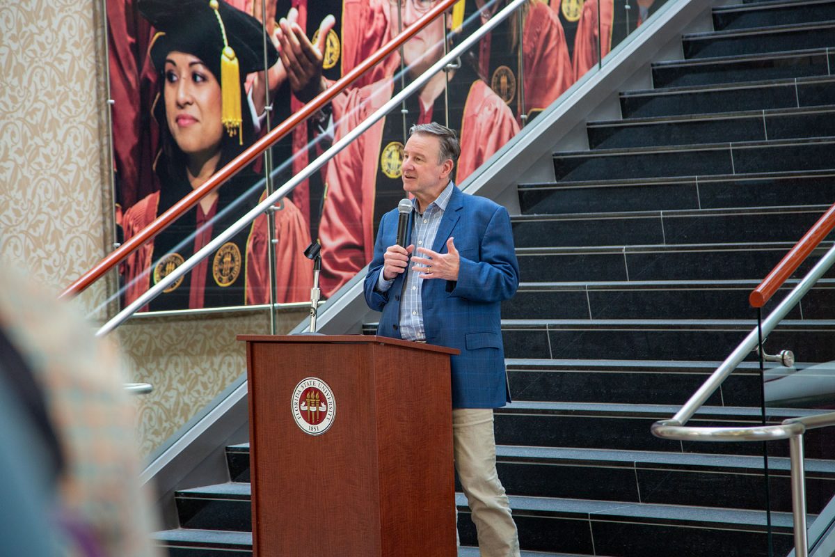 Man speaks into a microphone at a podium in front of stairs