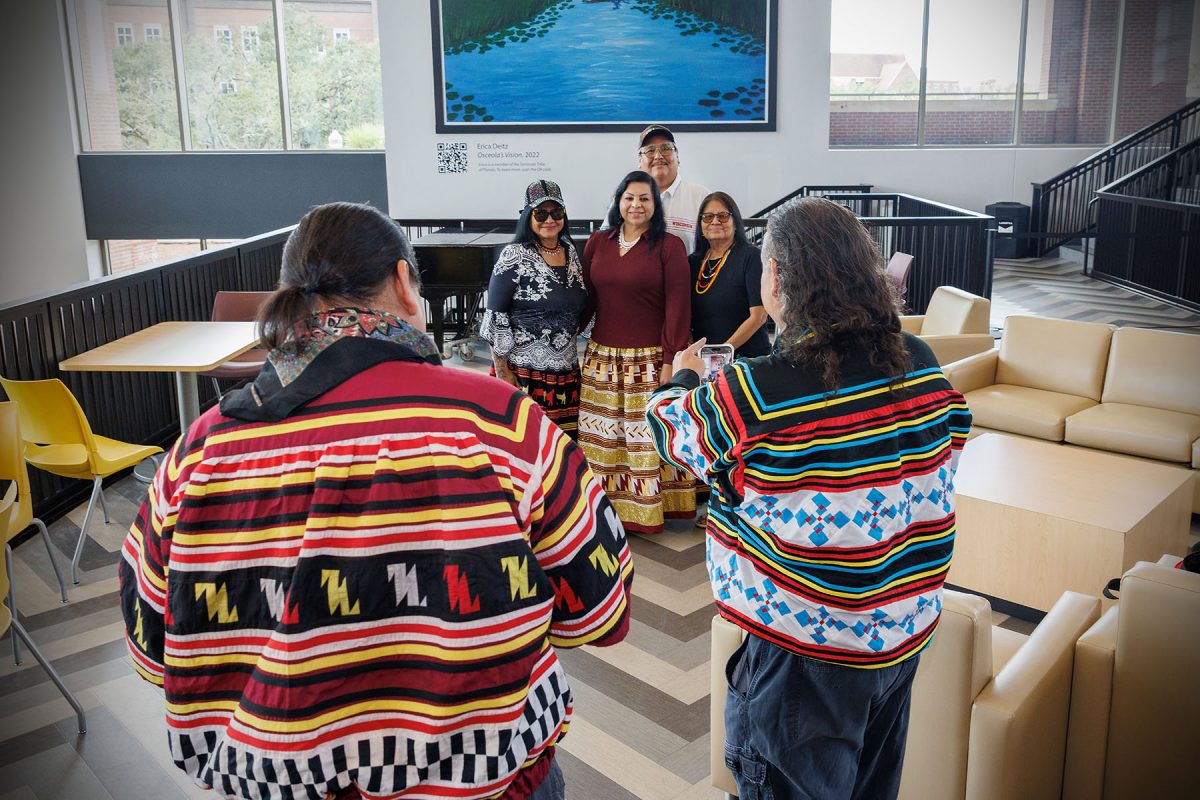 People pose for a picture taken by another person, all wearing clothing of the Seminole Tribe