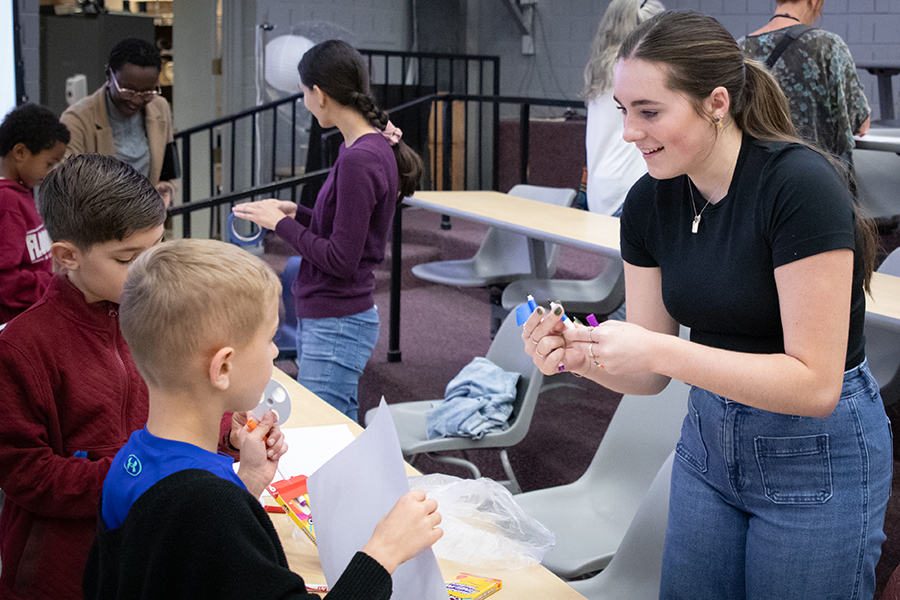Student interacts with child holding a piece of paper