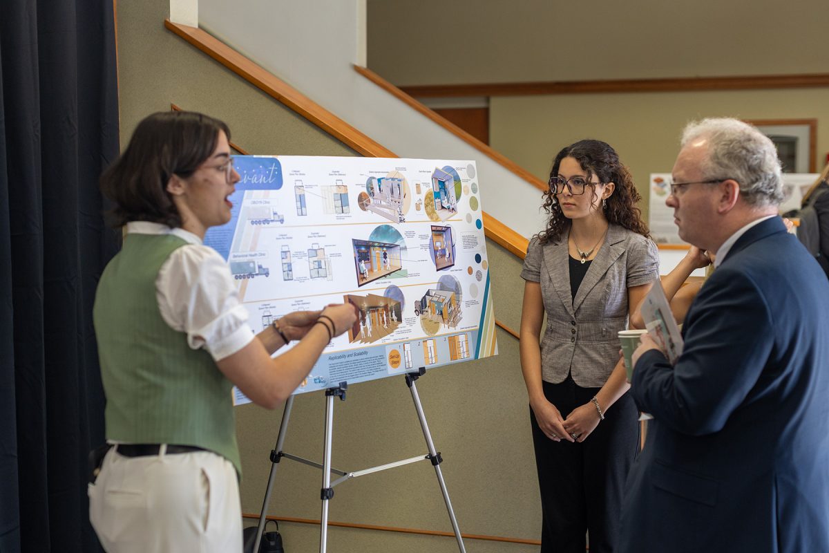 Three people discuss about a poster board project