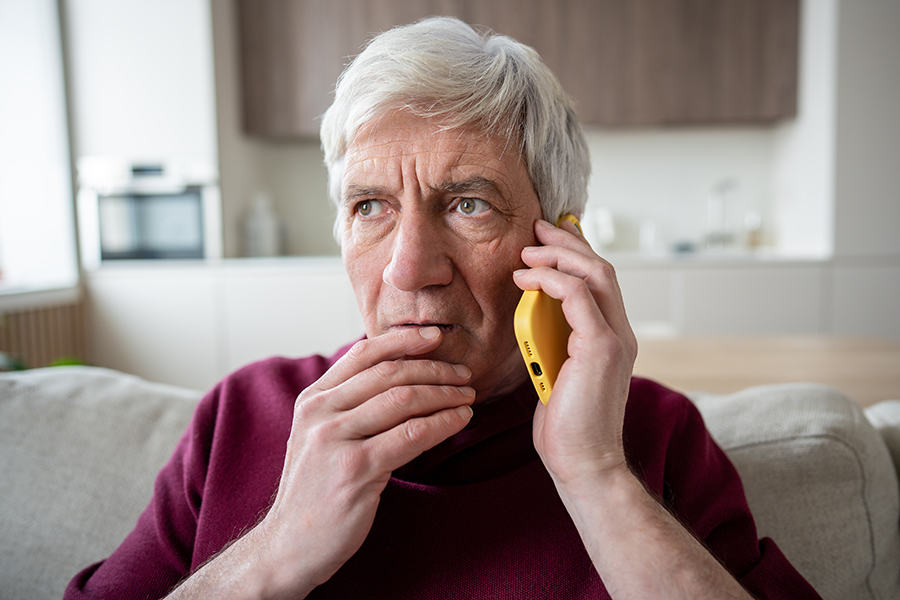 Older man acts surprise while holding up a cell phone to his ear