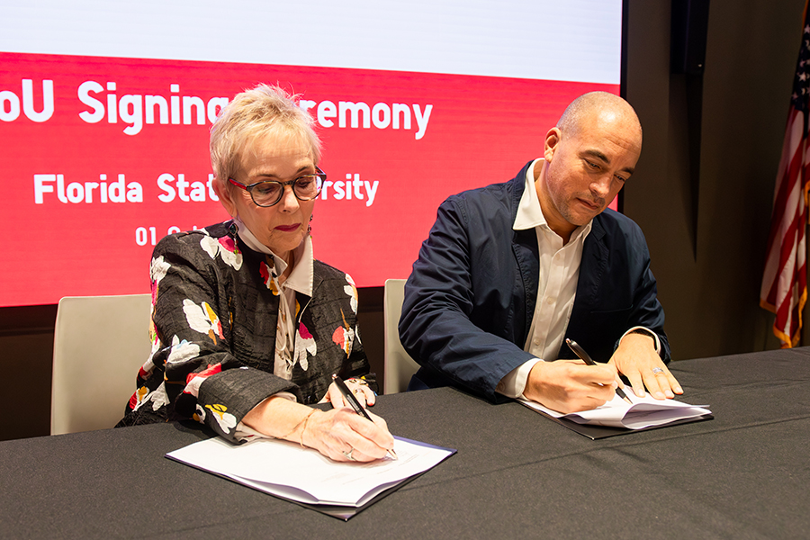 Two people sign papers at a table