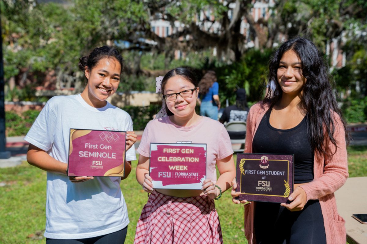 Three students holding up signs that celebrate being a First gen student
