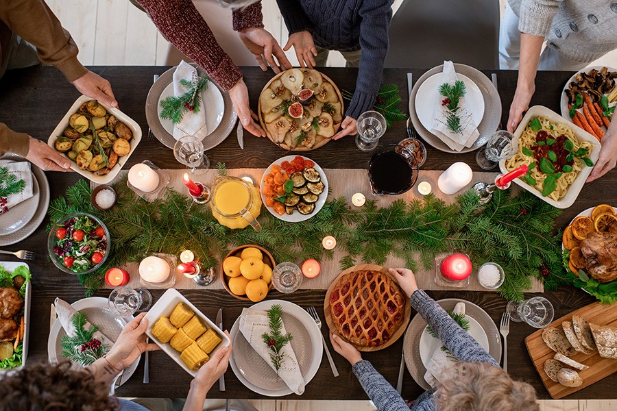 View of camera looking down on a table filled with food for Thanksgiving as people pass around plates.