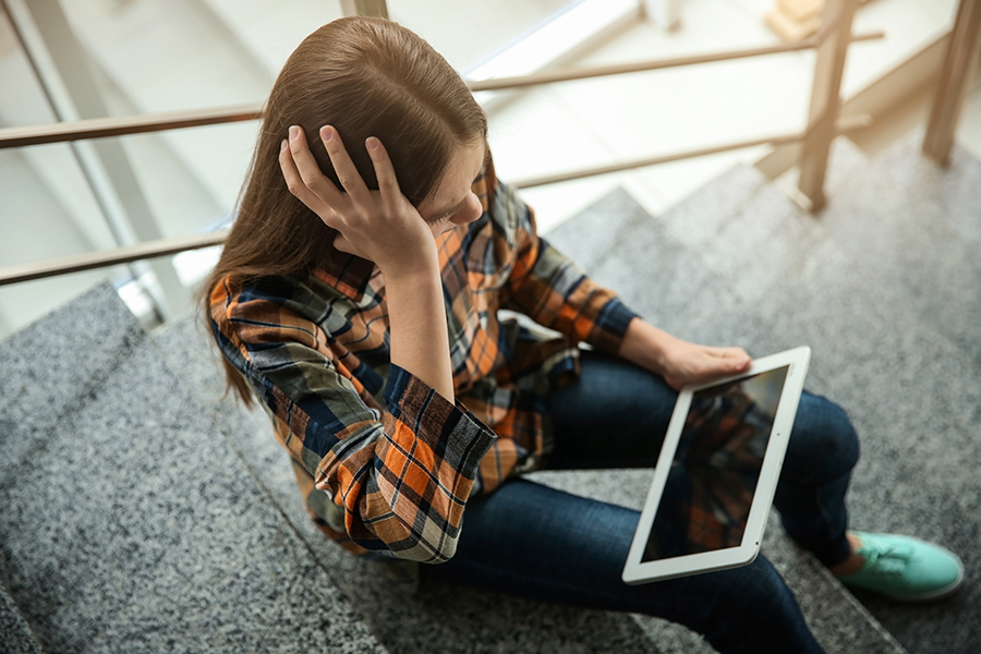 Person holds head while staring at a screen